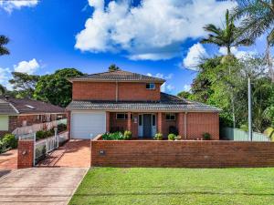 a brick house with a fence in front of it at Budge near the Beach in Budgewoi