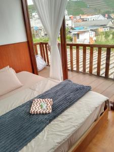 a bed with a bow tie sitting on a balcony at Cabin Wetan Kali Dieng in Diyeng