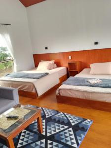 a hotel room with two beds and a coffee table at Cabin Wetan Kali Dieng in Diyeng +10 photos