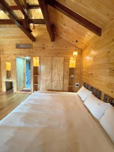 a large bed in a room with wooden walls at Homestay Gió Mộc !! in Làng Môn