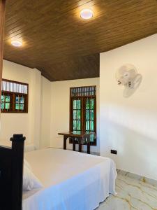 a bedroom with a white bed and a wooden ceiling at Sawmya Guest House in Randeniya