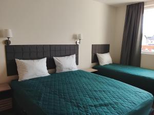 a bedroom with two beds with green covers and a window at Делта СПА in Banya