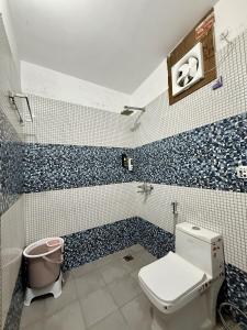 a bathroom with a toilet and blue and white tiles at Bunkyard rishikesh in Rishīkesh +14 photos