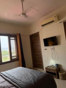 a bedroom with a bed and a tv and a window at Bunkyard rishikesh in Rishīkesh