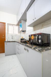 a kitchen with white cabinets and a microwave on a counter at Odilia Apartelle in Bangalore