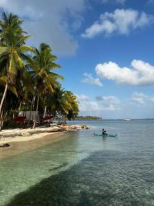 a person in a boat in the water near a beach at San Blas island cabins in Waisalatupo
