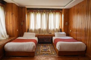 two beds in a room with wooden walls and curtains at Samyae Resort in Jakar