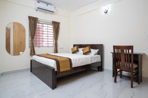a bedroom with a bed and a chair and a mirror at Odilia Apartelle in Bangalore