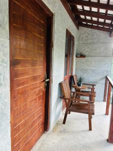 a porch with a wooden door and a wooden chair at SRI Villa in Busse