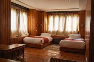 two beds in a room with wooden walls and windows at Samyae Resort in Jakar