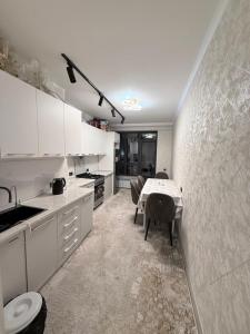 a kitchen with white cabinets and a table in it at Frunze Residence in Osh