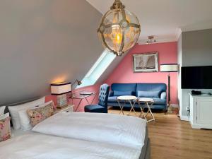 a bedroom with a bed and a couch and a chandelier at Hotel Norderriff in Langeoog +36 photos