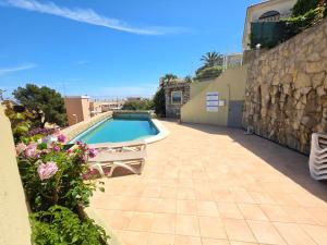 a swimming pool in a yard with a stone wall at ALBA MARINA Experience Peñiscola in Peniscola