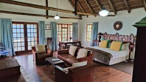 a bedroom with a bed and a couch and chairs at The Edge Mountain Retreat in Hogsback