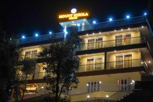 a hotel with a sign on top of it at night at Mount kirola stay in Bhowāli