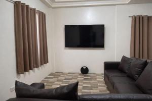 a living room with a couch and a flat screen tv at Tribo Zamani in General Luna