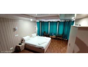 a bedroom with a bed and blue curtains at Hotel Alpine Ridge, Gulmarg in Gulmarg