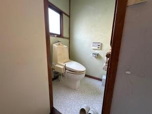 a bathroom with a toilet and a window at Guesthouse Azumaya 2nd in Matsumoto