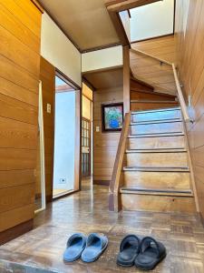 two pairs of shoes in a room with stairs at Guesthouse Azumaya 2nd in Matsumoto