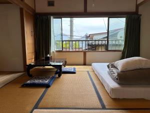 a bedroom with a bed and a table and a window at Guesthouse Azumaya 2nd in Matsumoto