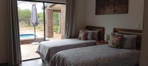 a bedroom with two beds and a sliding glass door at Vachellia View in Marloth Park