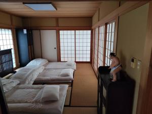 a man sitting on a suitcase in a room with beds at 夢尽くし in Aira