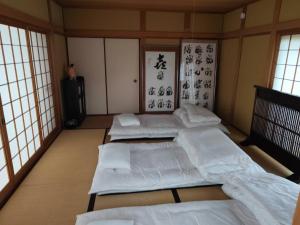 a room with four beds in a room with windows at 夢尽くし in Aira