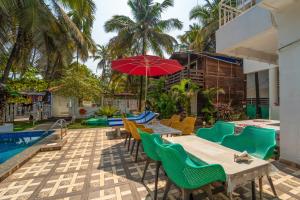 a patio with tables and chairs and a red umbrella at Beach Walk Resort Walk In Morjim Beach Goa in Morjim