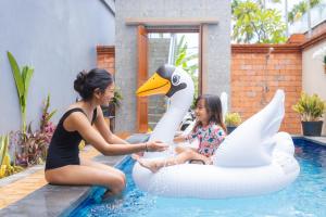 two women sitting on an inflatable swan in a swimming pool at Alam Canggu Kuta by ABM in Canggu