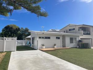 a white house with a fence and a yard at Silver Sands Villa in Mandurah