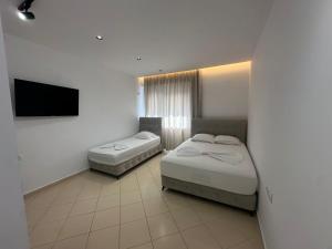 a bedroom with two beds and a flat screen tv at Villa Klaus in Lukovë