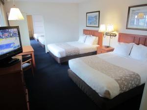 a hotel room with two beds and a flat screen tv at Newport Channel Inn in Newport Beach