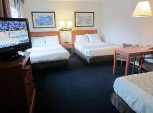 a hotel room with two beds and a flat screen tv at Newport Channel Inn in Newport Beach