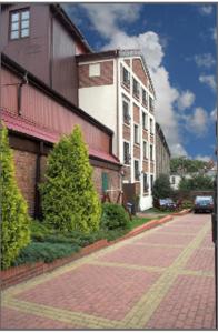 a brick sidewalk in front of a building with a tree at Pensjonat Oleńka in Ustka