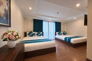 a hotel room with two beds and a vase with flowers at Calla Lily Hotel in Sapa