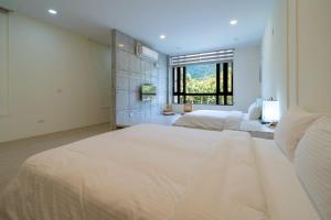 a large white bedroom with two beds and a window at 伊旅旅宿民宿 in Guangfu