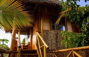 a wooden house with a palm tree in front of it at Mbao Boutique Bungalows in Jambiani