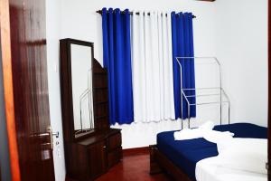 a bedroom with blue curtains and a bed and a mirror at Villa - Nil Vimana - Ella in Ella