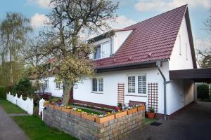 a white house with a red roof and a brick wall at Pension An der Bleiche in Wustrau