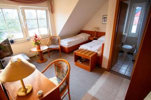 a small room with a bed and a table and chairs at Pension An der Bleiche in Wustrau
