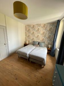 a bedroom with a bed and a wall with wallpaper at Le gîte de Marie in Gramat