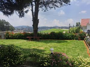 a park with a tree and a bench and flowers at Milestone Heritage Inn in Jāmb