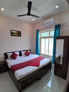 a bedroom with a bed with red pillows and a window at Himalayan Wellness Retreat in Rishīkesh