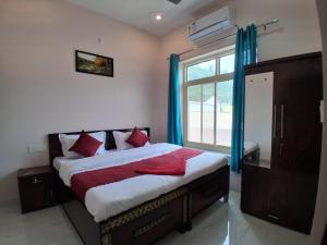 a bedroom with a bed with red pillows and a window at Himalayan Wellness Retreat in Rishīkesh