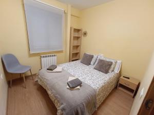 a small bedroom with a bed and a chair at Piso Rualte in Ávila