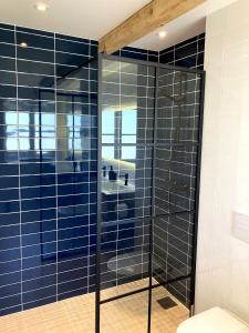 a shower in a bathroom with blue tiles at Solhjem Bornholm - Top Rated Sea View Stay in Gudhjem +9 photos