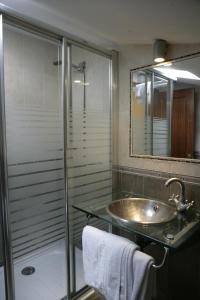 y baño con lavabo y ducha acristalada. en Hotel Azpiazu, en Muros de Nalón
