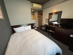 a bedroom with a bed and a desk and a mirror at Hotel Route-Inn Shibukawa in Shibukawa