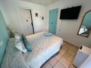 a bedroom with a bed with blue pillows and a tv at La Puerta Azul in Jávea