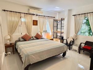 a bedroom with a bed and a chair and windows at Banyan House Samui bed and breakfast (Adult Only) in Chaweng